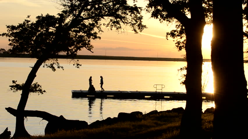 YUBA CITY, CALIFORNIA-CIRCA 2011-Three young women watching the sunset from the dock at Far West Reservoir near Spenceville Wildlife Area, Yuba City, California.