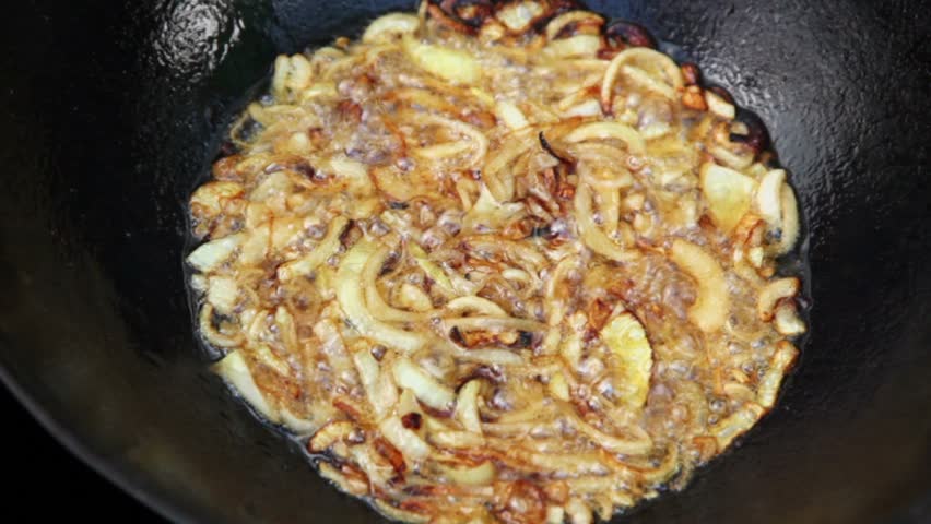 Lot of broiled onion boils in hot oil at pot closeup