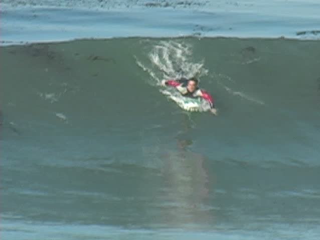 A surfboarder catching a wave in slow-motion and then accelerated.