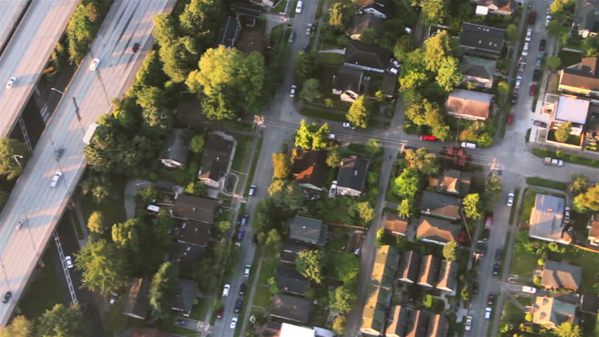 Overhead right pan across houses, yards and cars along suburban street