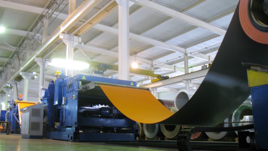 Wide sheets of metal are braided in big rolls at plant, time lapse