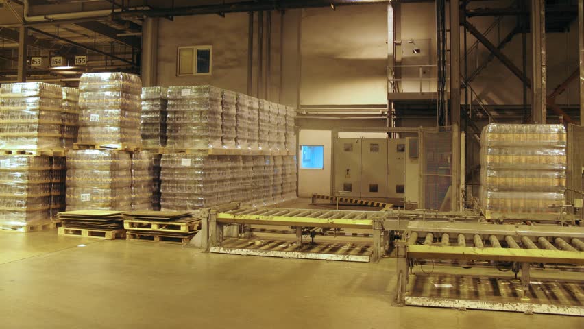 Special crane lowers containers with kvass bottles on warehouse of nonalcoholic plant, time lapse
