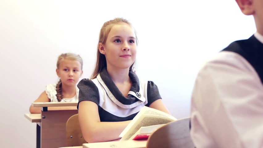 Adorable smart schoolgirl raising hand and giving answer