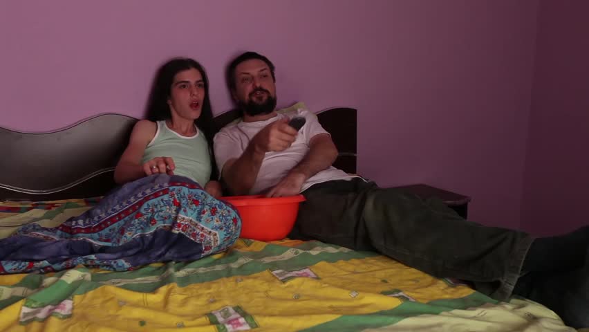 Young adult couple zaps and eats popcorn and snacks.
