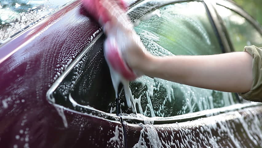 Unrecognizable female person washing car by sponge