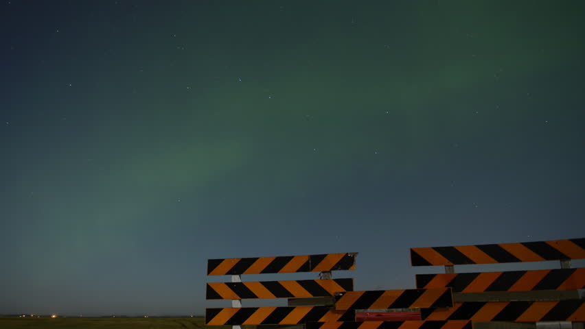 The Aura Borealis captured in timelapse photography behind a road barrier.