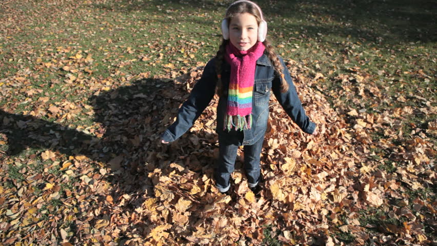 Girl falling into the heap of autumn leaves and lying there comfortably