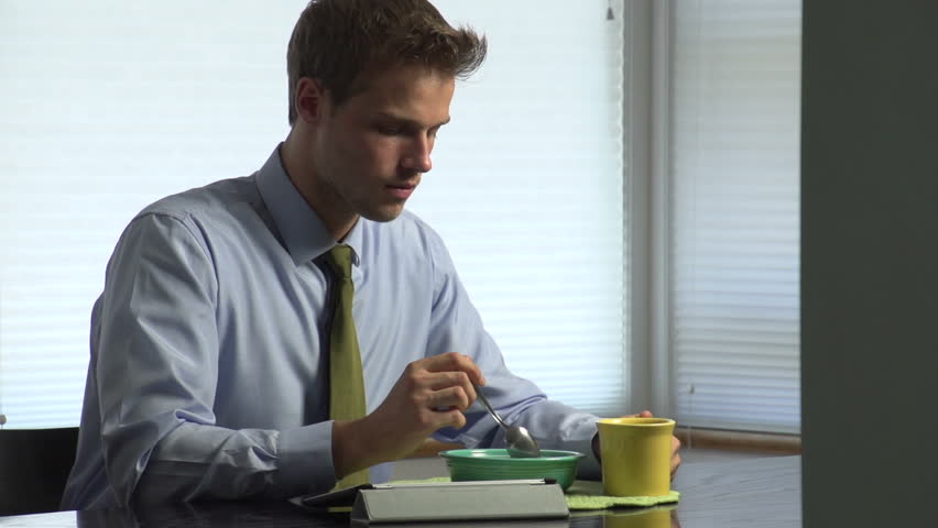 Man eating breakfast before work with tablet