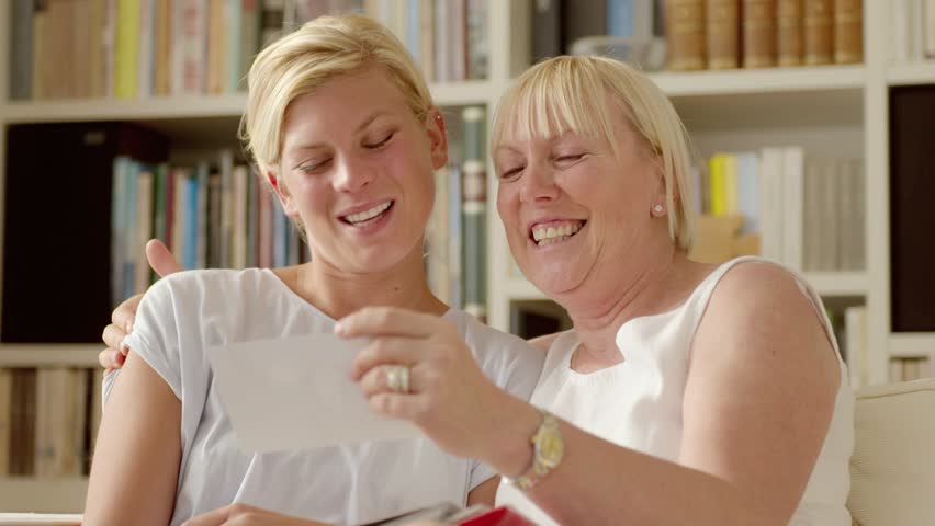 Family happiness and memories, happy mother and daughter looking at pictures in photo album at home