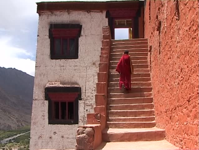 Monk is climbing up monastery entrance in Ladakh