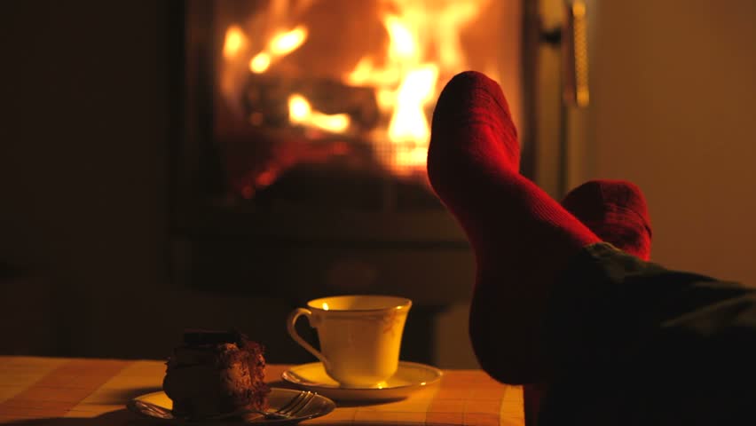 Man relaxes by warm fire and wriggles his toes.