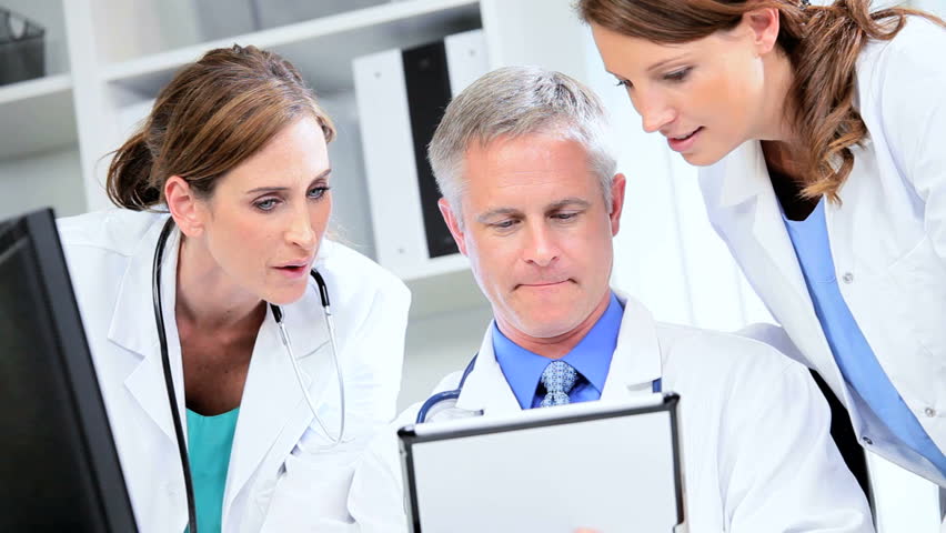 Female male Caucasian doctors planning patient care using information wireless tablet technology