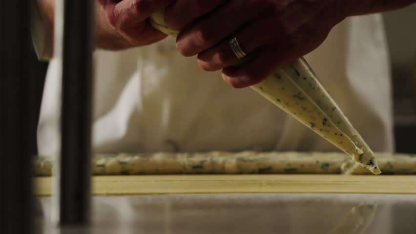 Chef uses a pastry bag to fill pasta with ricotta and spinach mix.