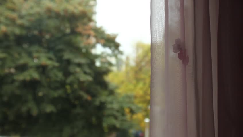 Young adult woman comes to window and speaks to an off camera character.
