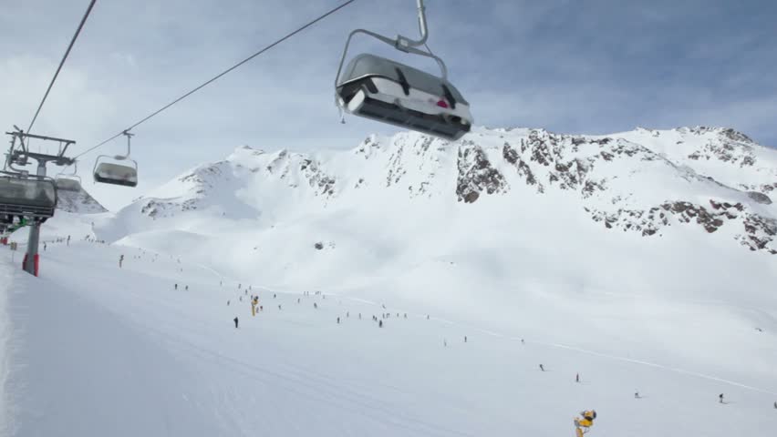 Ski chair-lift with skiers in snow-capped mountains at Austrian Alps