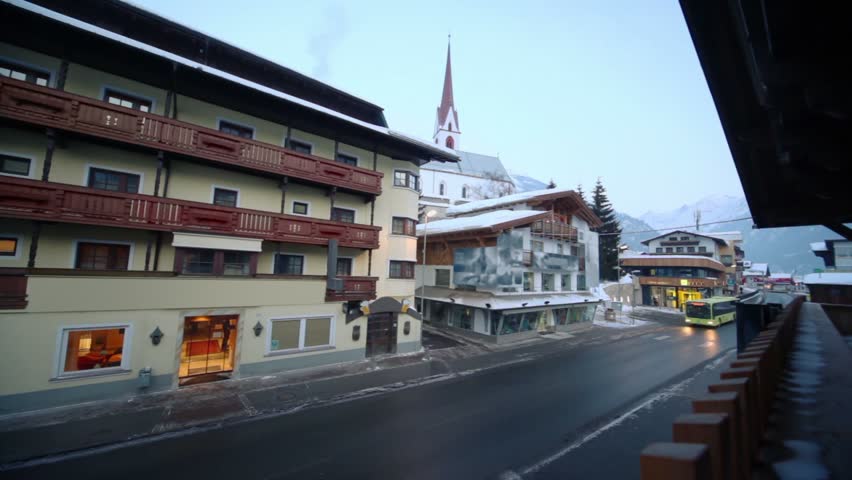 Bus passes by street in small town near mountain with forest on winter day