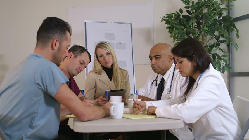 Lovely blond pharmaceutical saleswoman and group of doctors sitting at a table listening to her presentation. Canon C300