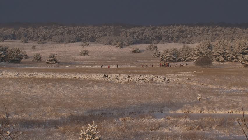 Snow covered landscape, skaters in distance. The Dutch Veluwe landscape still carries the marks of the ice age.