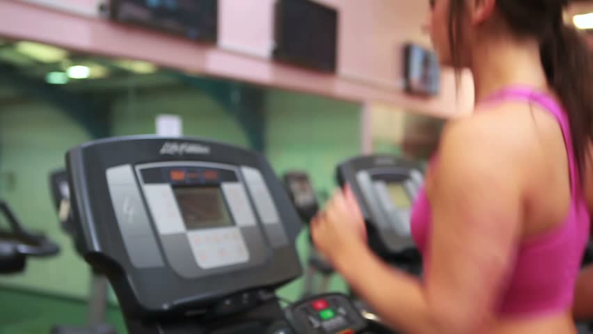 Woman energetically running on treadmill in gym