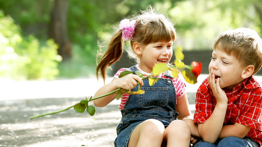 Two child speaking and boy present flower