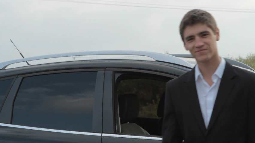 Smiling businessman with keys next to car