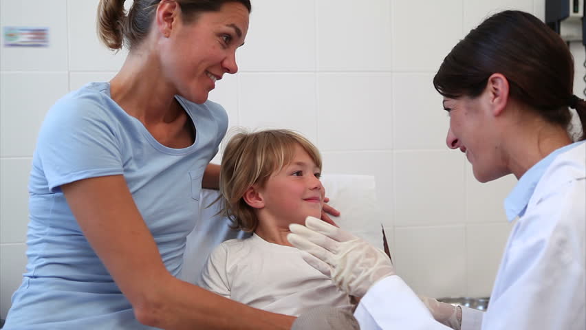 Serious doctor giving child an injection in examination room