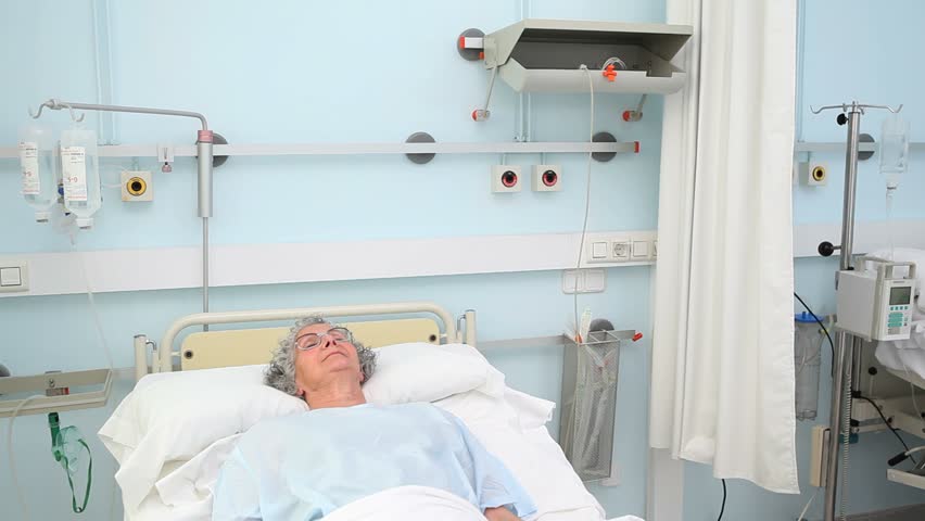 Intern holding a patient hands while siting on a hospital bed
