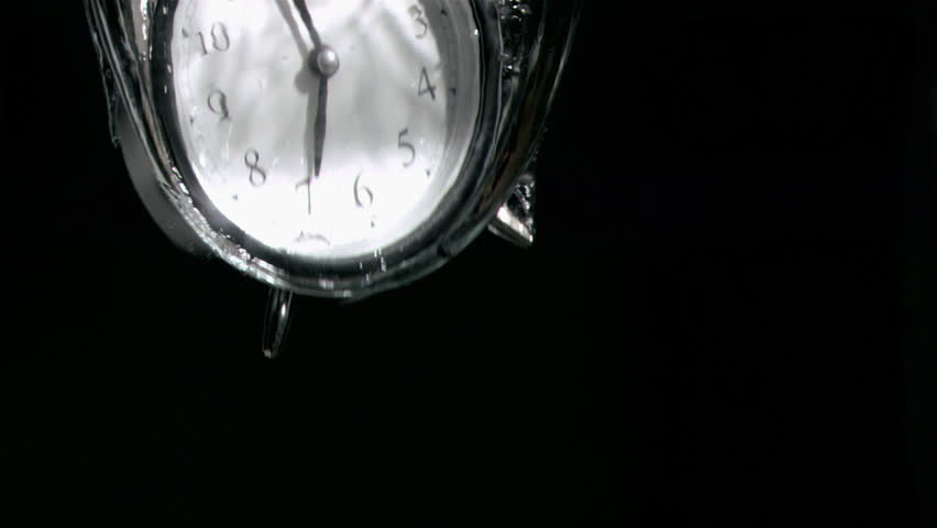 Alarm clock in a super slow motion falling in water against a black background
