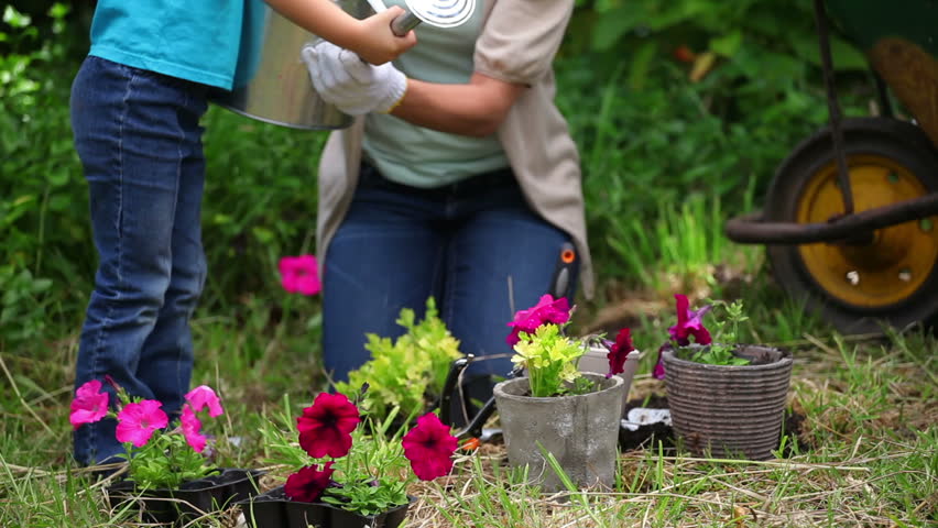 Mother and daughter watering flowers together in a garden