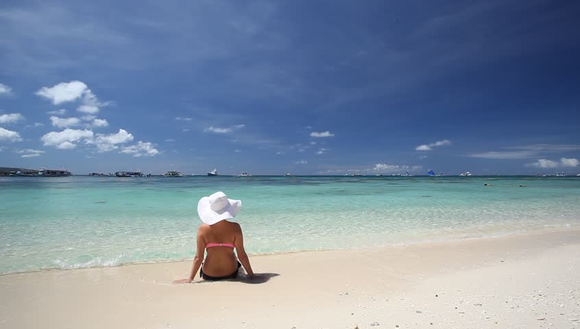 Woman in summer hat relaxing on caribbean beach