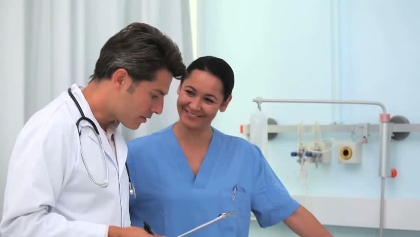 Doctor and nurse talking with a patient in hospital ward
