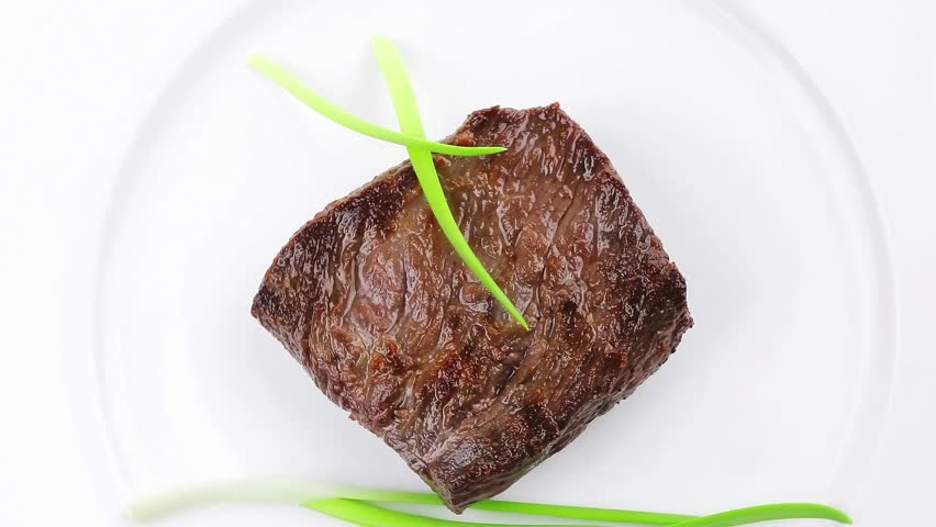 meat savory : grilled beef fillet mignon on white plate with green onion sprouts isolated over white background
