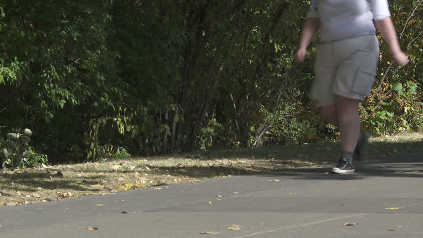 Obese person walking on a city pathway 