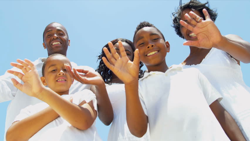 Ethnic sons and daughter with parents waving on video postcard