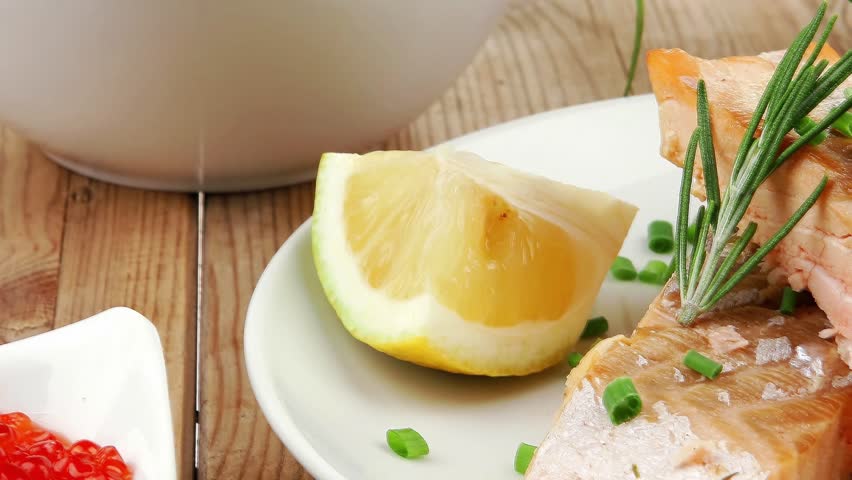 savory sea fish : baked salmon strips with green vegetable salad and tomatoes red caviar in white bowl grinder and cutlery on wooden table