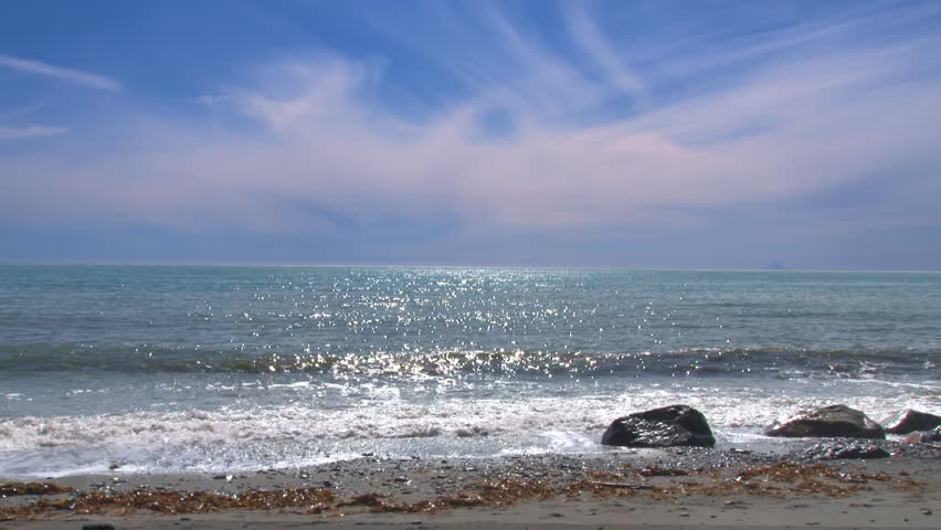 Timelapse sky and clouds over real time water waves and beach.
