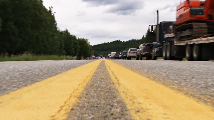Extreme low angle shot starting with a fast zoom from wide to tele of an accident scene on an Alaskan highway involving a head-on fatality.