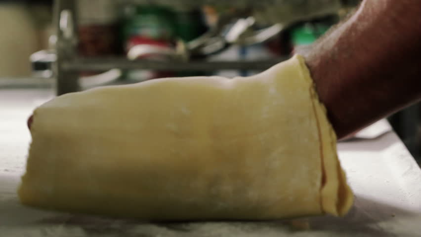 Chef prepares dough for making pasta, flouring the dough and kneading it
