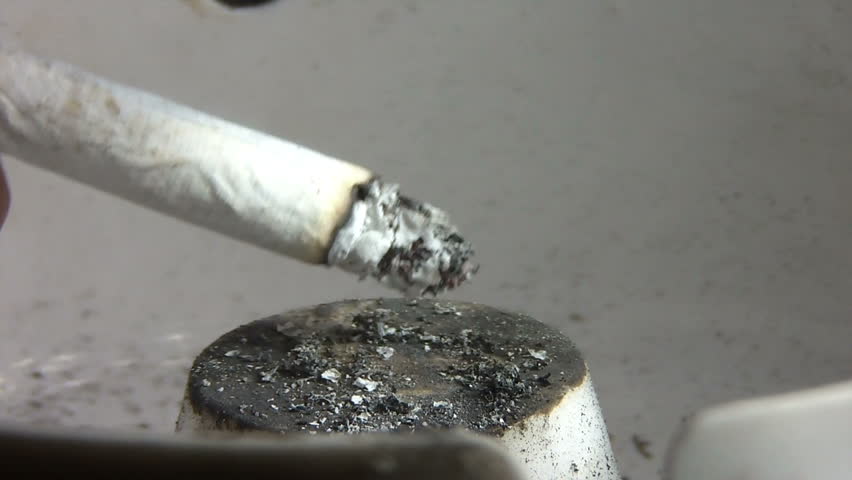 Cigarette burning in a filthy ashtray 
