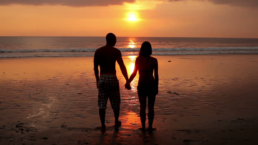 Couple walking on beach with dog at sunset in Bali