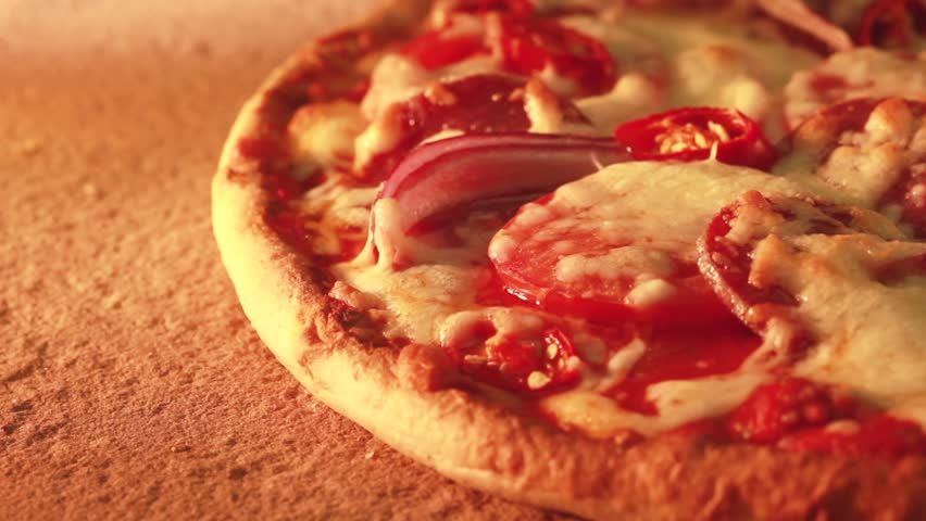 A salami pizza being baked in a wood-fired oven