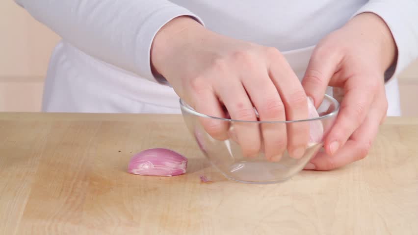 Shallots in a bowl being drizzled with olive oil