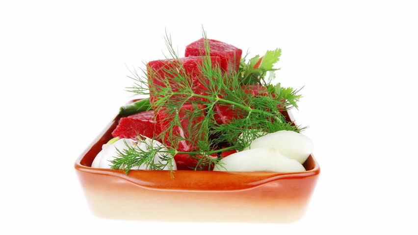uncooked fresh beef meat chunks on ceramic bowls with vegetables and greenery isolated over white background