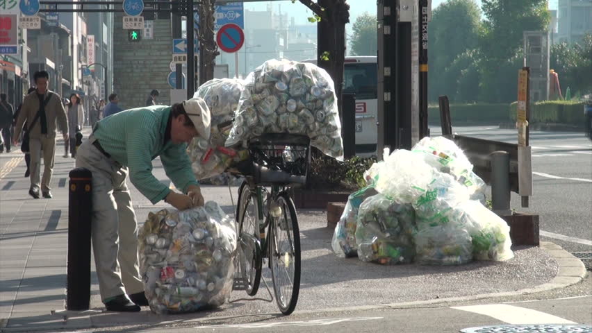 KYOTO, JAPAN - 26 OCTOBER 2012: A man is collecting cans for recycling purposes, using his bicycle for transportation, on the streets of Kyoto in Japan