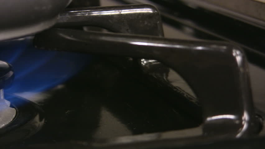 HD 1080i fast pan of of a pan warming over a gas stove's blue flame.