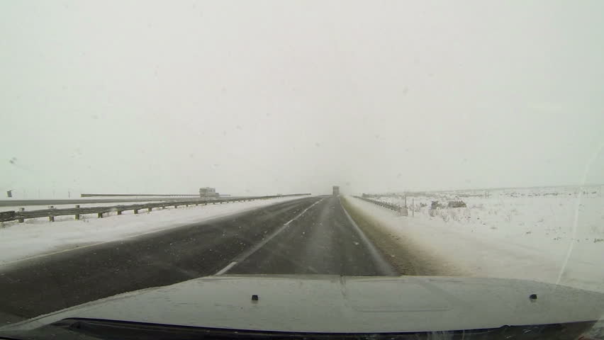 NEPHI, UTAH 26 DEC 2012: Winter snow blizzard freeway road driving. Ice and snow on road. First person point of view (POV) looking through drivers windshield. Rural farm community and mountain roads.