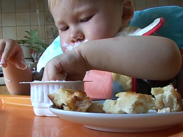 Baby learning to feed himself with a spoon and getting messy in the process
