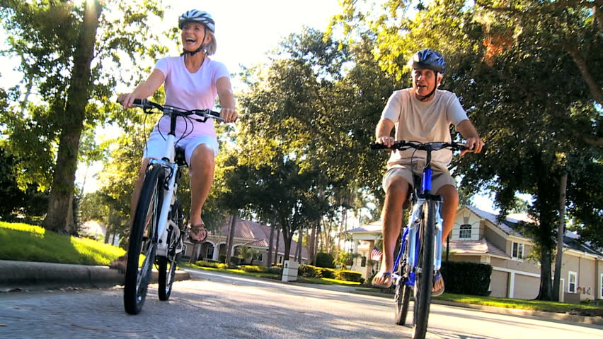 Fit & healthy senior couple enjoying retirement cycling outdoors in the sunshine