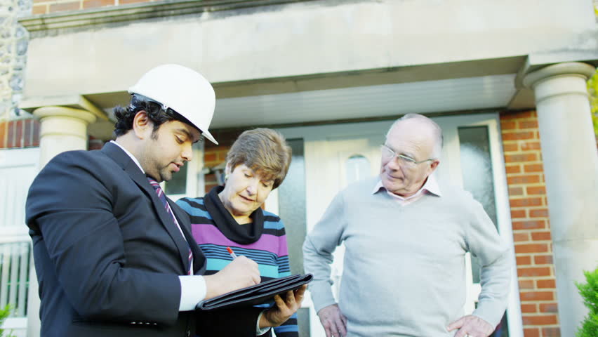 A happy and friendly elderly couple hire a surveyor to give them a quote for some building alterations to be done to their house. In slow motion.