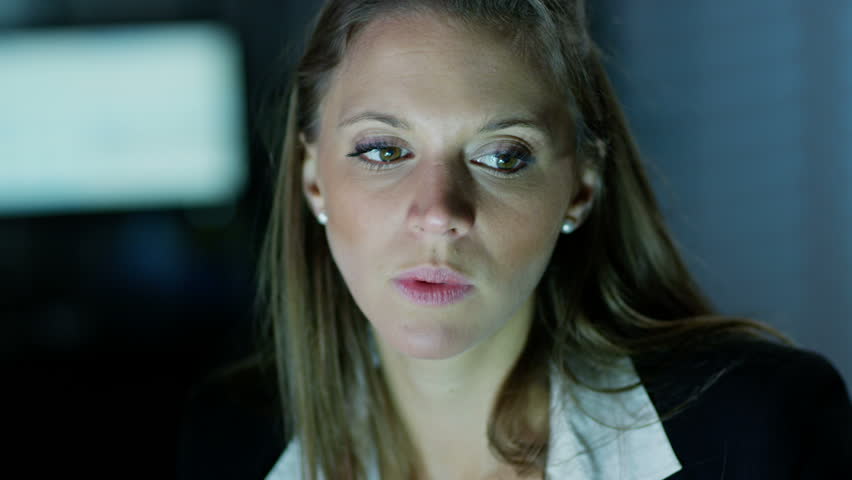 Close up of two professional female businesswomen working late in an office that is full of computer monitors. They are discussing what they see on the computer screen. In slow motion.